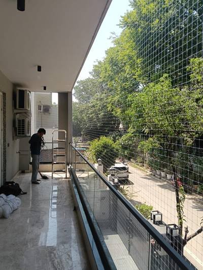 Anti bird net installation across a covered building corridor