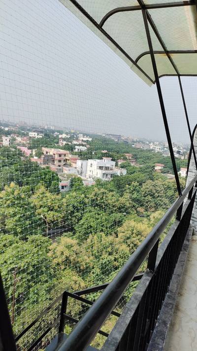 Anti bird net enclosing a terrace canopy surrounded by trees