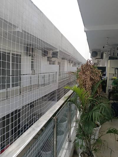 Anti bird net fitted along a long open walkway balcony