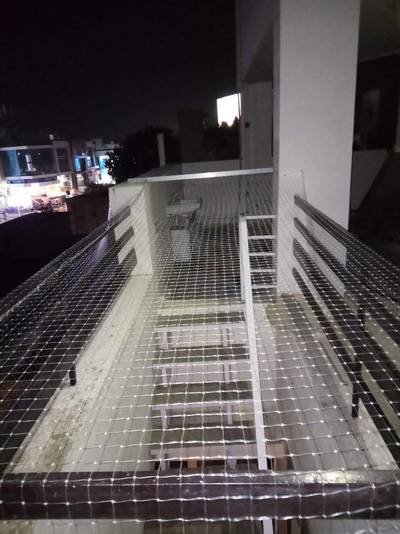 Balcony safety net photographed in the evening with city lights behind