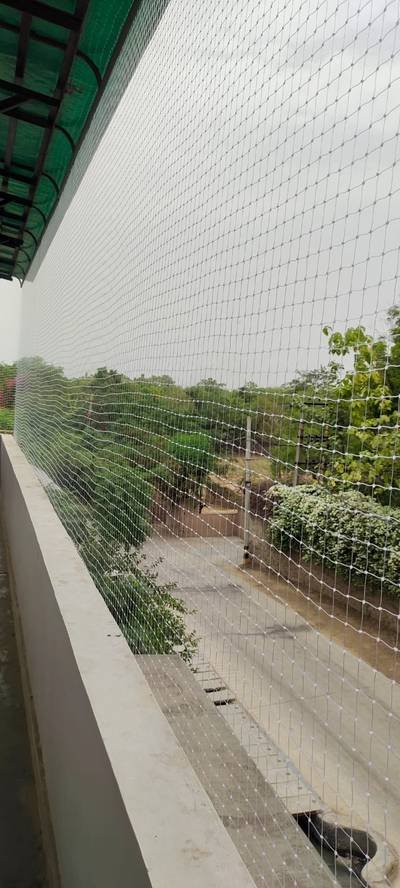 Bird net stretched across an open boundary beside greenery