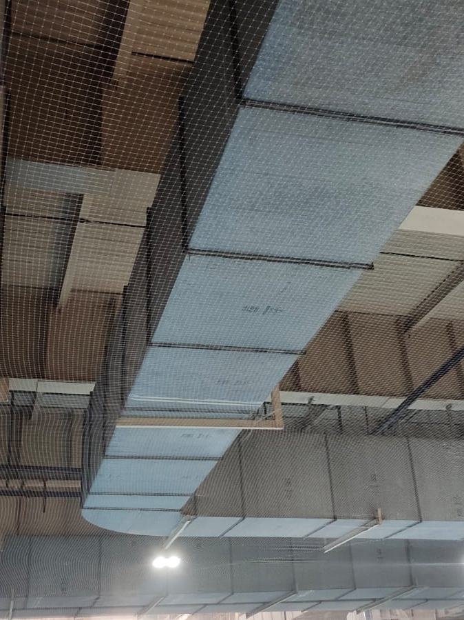 Commercial bird net installed at ceiling level around ducting in a service bay