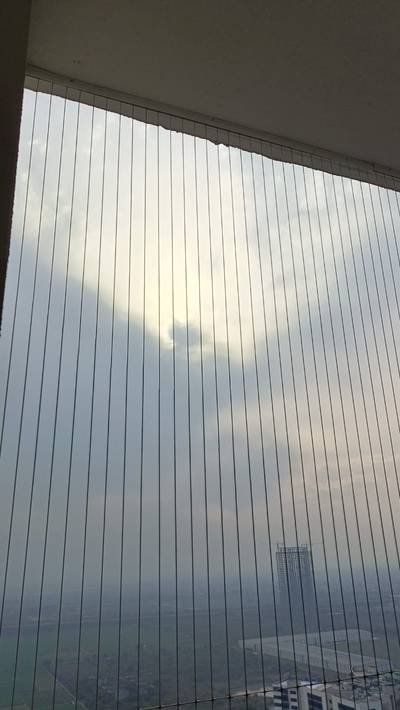 Invisible safety grill with closely spaced vertical stainless cables against the sky